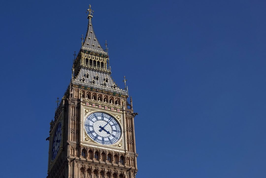 LONDON'S ICONIC BIG BEN CLOCK TOWER STANDS AGAINST A CLEAR BLUE SKY