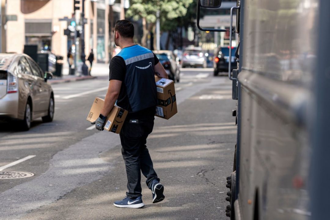 A worker delivers Amazon packages on an urban street