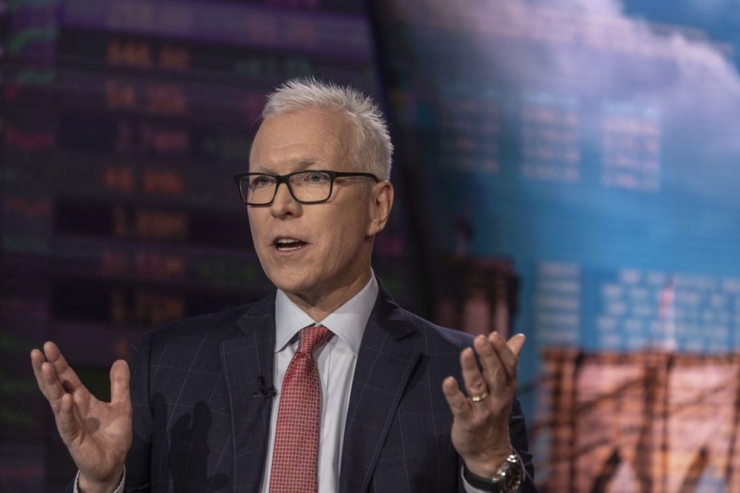 A BESPECTACLED GREY-HAIRED MAN IN SUIT, TIE AND EXPENSIVE WATCH HOLDS HIS HANDS UP IN A GESTURE OF EXPLANATION