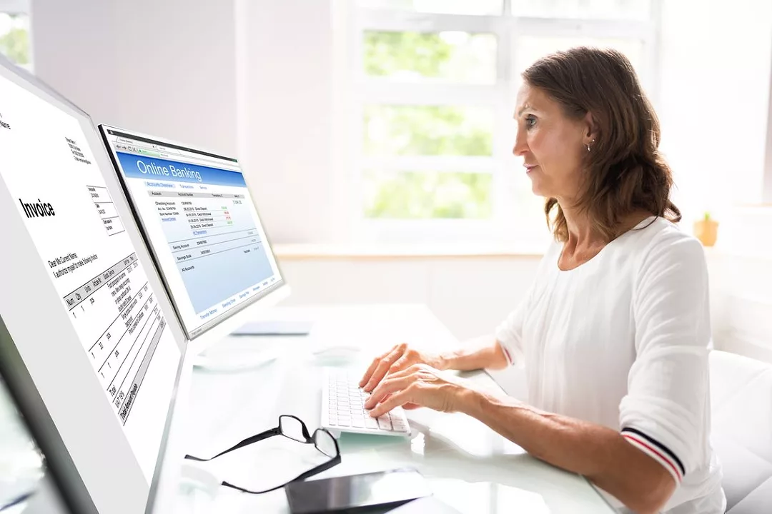 A WOMAN TYPES AT A COMPUTER SHOWING INVOICING