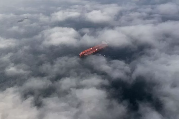 A HIGH AERIAL SHOT OF AN OIL TANKER ON THE OCEAN, SEEN THROUGH CLOUDS