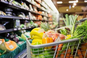 A LOADED SUPERMARKET CART STANDS IN A SUPERMARKET AISLE