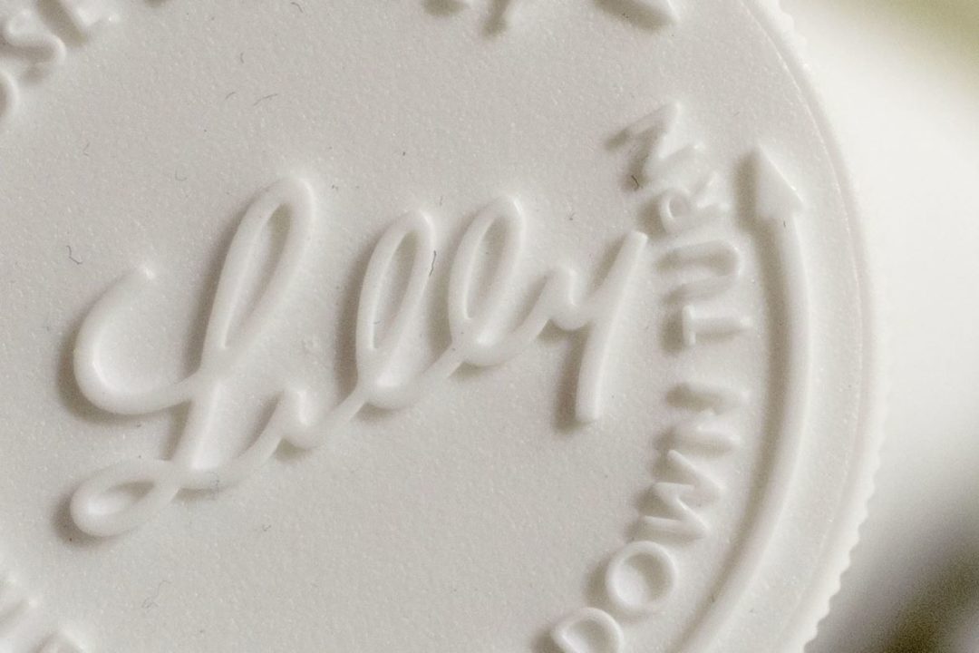 AN EXTREME CLOSE UP OF A CHALKY, WHITE PILL STAMPED WITH THE NAME LILLY