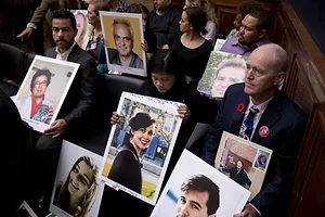 A GROUP OF RELATIVES HOLDS UP PHOTOS OF THEIR LOST LOVED ONES