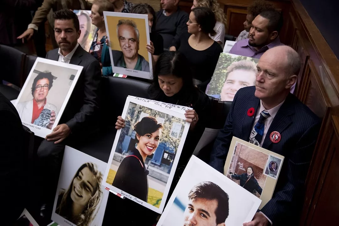 A GROUP OF RELATIVES HOLDS UP PHOTOS OF THEIR LOST LOVED ONES