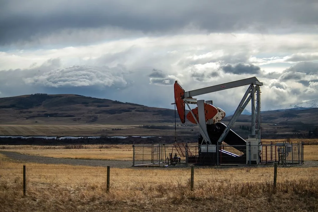 A LONE OIL DERRICK STANDS IN A VAST PRAIRIE