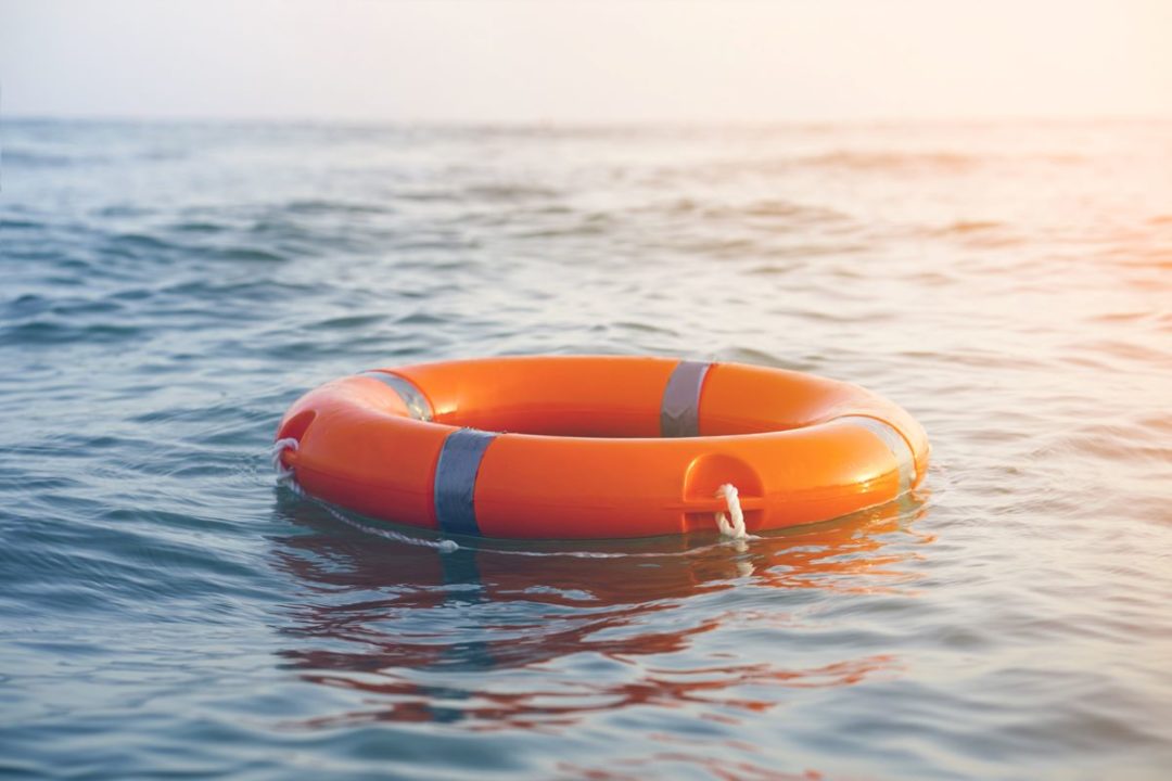A ROUND, ORANGE LIFE PRESERVER RING FLOATS ON THE SURFACE OF THE OCEAN