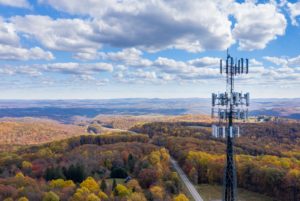 A WIRELESS CELL TOWER STANDS AGAINST A STUNNING VISTA OF ROLLING HILLS IN FALL COLORS