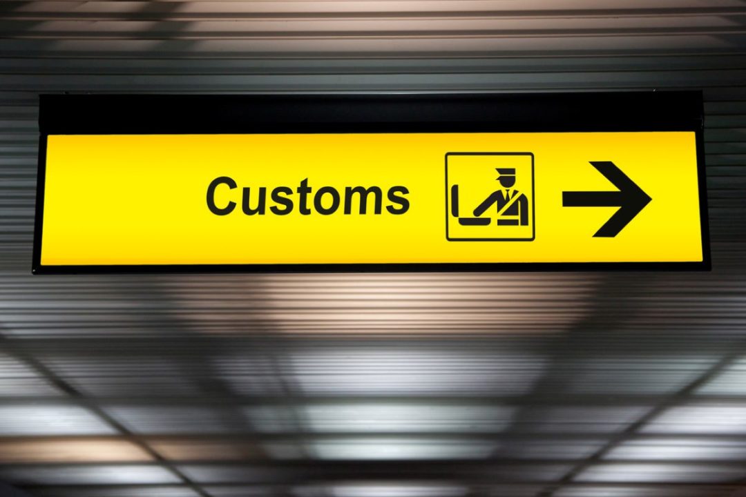 A LIGHTED YELLOW SIGN DISPLAYS THE WORD CUSTOMS