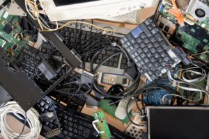 A PILE OF DISCARDED ELECTRONIC COMPONENTS, INCLUDING KEYBOARDS, LIES JUMBLED TOGETHER