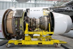 A LARGE AIRCRAFT ENGINE SITS IN A HANGAR WITH ITS COVERS OFF FOR MAINTENANCE