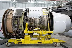 A LARGE AIRCRAFT ENGINE SITS IN A HANGAR WITH ITS COVERS OFF FOR MAINTENANCE