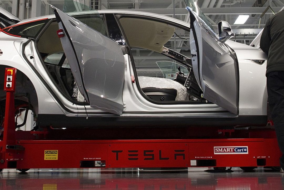 A NEAR-COMPLETED CAR SITS ON A TESLA PRODUCTION LINE