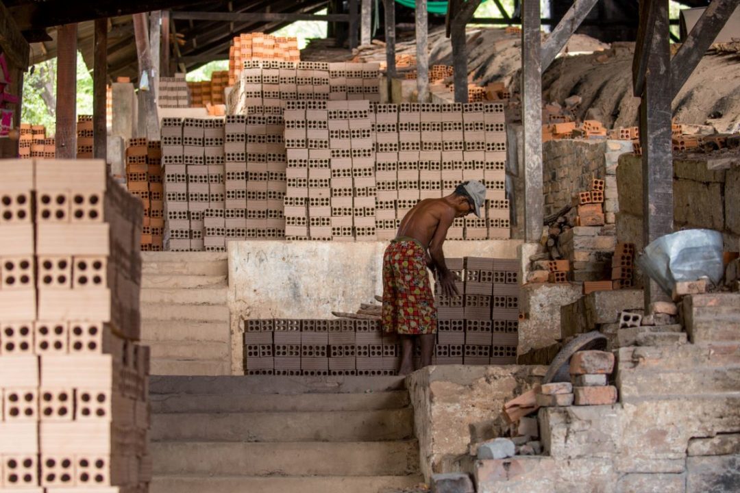 A WORKER IS SURROUNDED BY TOWERS OF BRICKS IN A WAREHOUSE