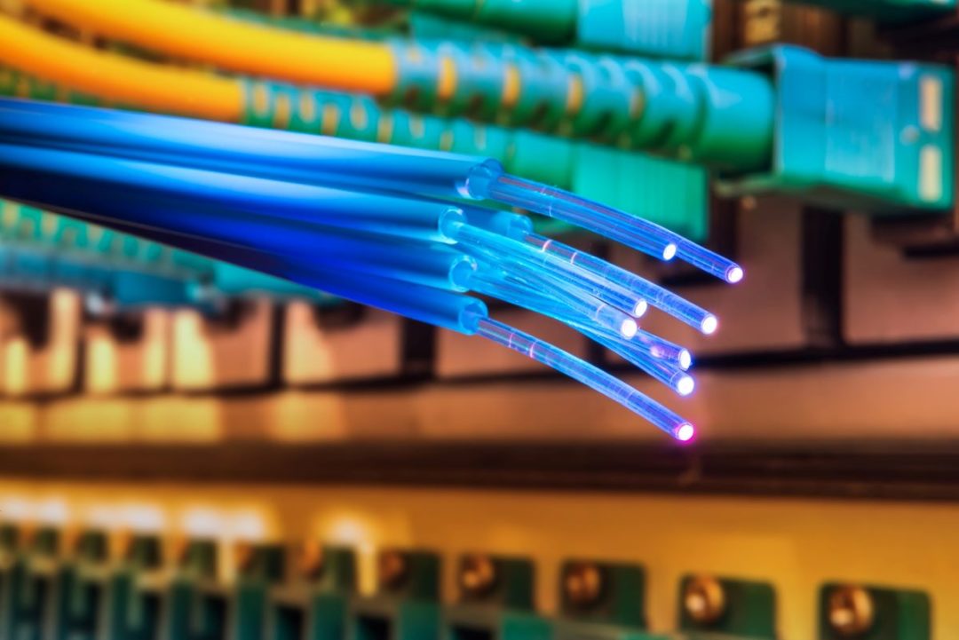 A CLOSE-UP VIEW OF A CLUSTER OF BRIGHT BLUE FIBER OPTIC CABLES