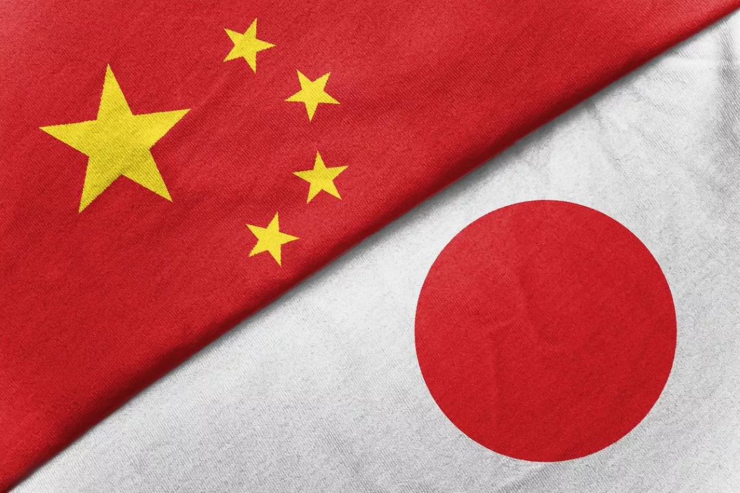 THE FOLDED FLAGS OF JAPAN AND CHINA LIE NEXT TO ONE ANOTHER