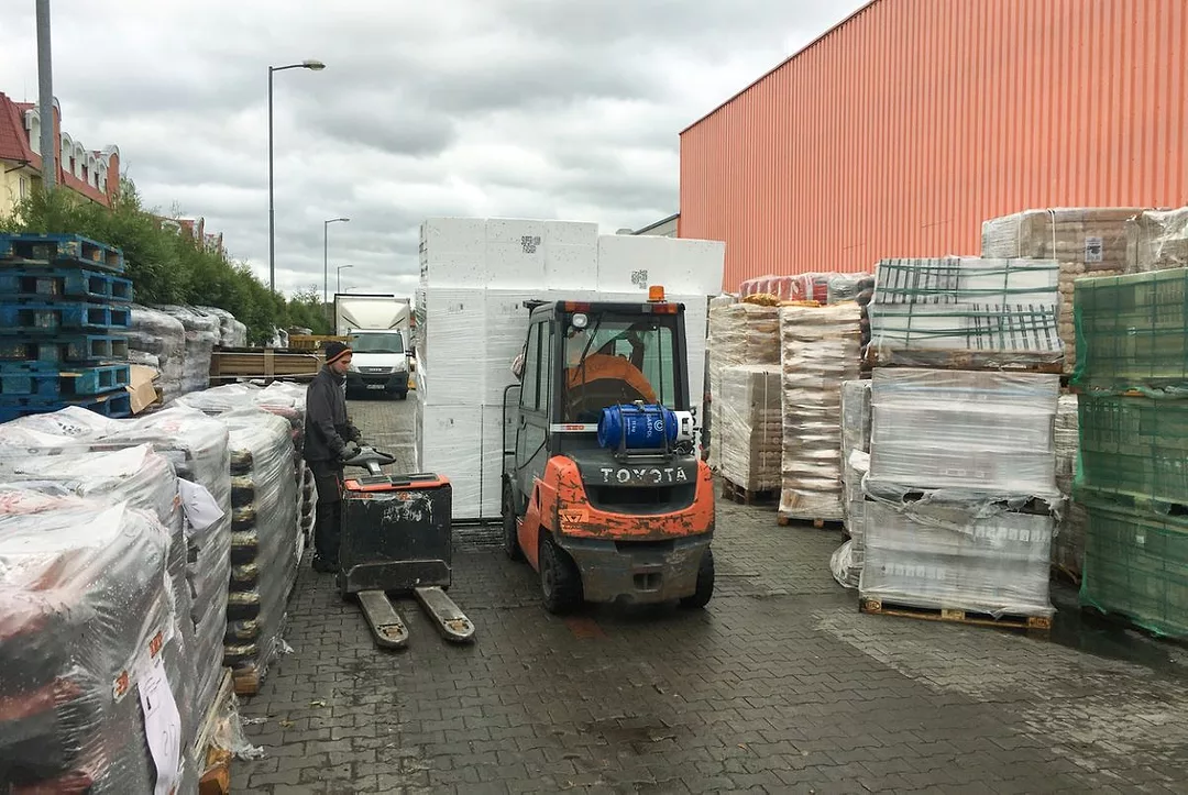Two fork lifts pass each other unloading merchandise in an overcrowded storage area