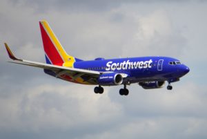 A PLANE BEARING THE RED GOLD AND BLUE COLORS OF SOUTHWEST AIRLINES FLIES THE SKIES