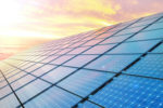A close-up of solar panels can be seen in front of a sunset. Photo: iStock.com/JONGHO SHIN