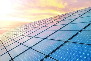 A close-up of solar panels can be seen in front of a sunset. Photo: iStock.com/JONGHO SHIN
