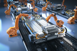 MULTIPLE ORANGE ROBOTIC ARMS ON AN ASSEMBLY LINE ARE BUILDING A CAR WITH ELECTRIC CAR BATTERY CELLS