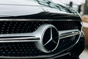 A CLOSE-UP OF A SILVER AND BLACK MERCEDES-BENZ LOGO ON THE FRONT OF A BLACK CAR.