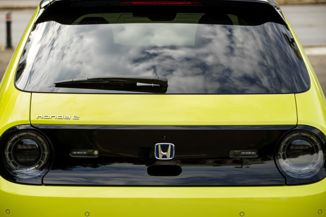 THE REAR OF A BRIGHT YELLOW CAR BEARS THE HONDA DECAL 