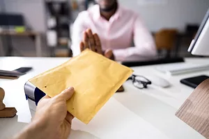 A MAN REFUSES A BRIBE BEING OFFERED OVER A DESK