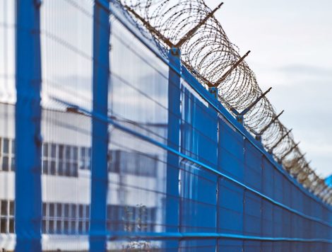 A ROW OF COMMERCIAL BUILDINGS IS VISIBLE BEYOND A FENCE OF BARBED WIRE