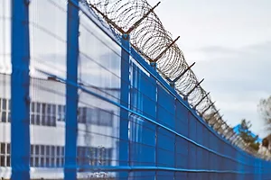 A ROW OF COMMERCIAL BUILDINGS IS VISIBLE BEYOND A FENCE OF BARBED WIRE