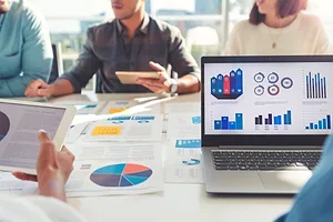 Group of people meeting with lots of charts on their laptops and paperwork