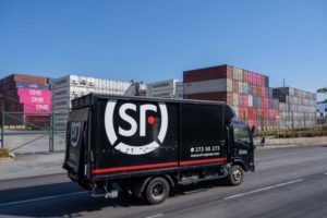 A DELIVERY VAN BEARING THE SF EXPRESS LOGO DRIVES PAST A STACK OF CONTAINERS