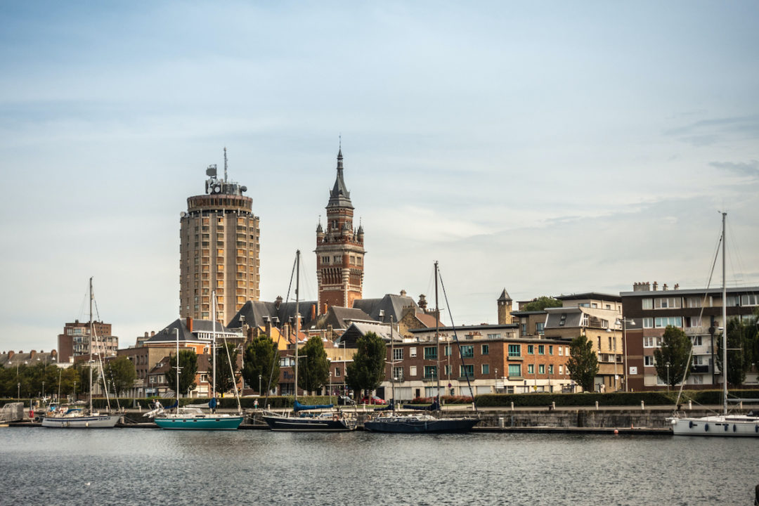 Old Port with sailing yachts and two towers: condominiums, Belfry of Dunkirk town hall under light blue sky. Dunkerque, France. September 16, 2018. Photo: iStock.com/ClaudineVM