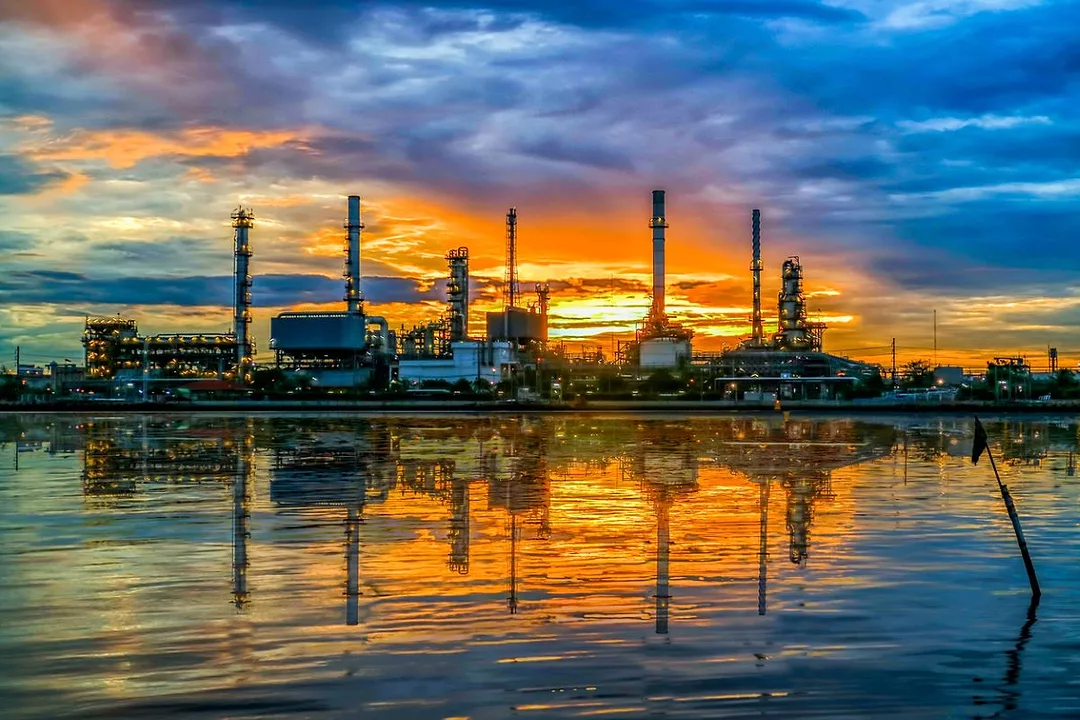 A MANUFACTURING PLANT AT DUSK OR DAWN REFLECTED IN WATER