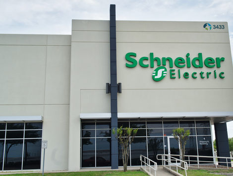THE EXTERIOR OF A SCHNEIDER ELECTRIC OFFICE BUILDING IN FRONT OF A CLOUDY SKY.