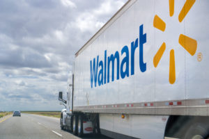 A Walmart truck is driving on a highway on a cloudy day. 