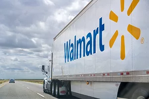 A Walmart truck is driving on a highway on a cloudy day. 