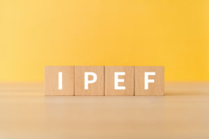 FOUR WOODEN BLOCKS EACH SPELL OUT "IPEF" WITH ONE LETTER ON EACH BLOCK IN FRONT OF A YELLOW BACKGROUND.