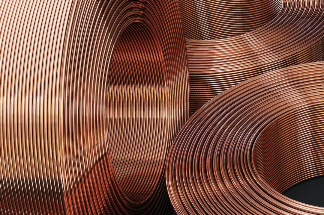 THREE ROUND SPOOLS OF COPPER PIPES CAN BE SEEN. TWO ARE SITTING HORIZONTALLY WHILE ONE IS VERTICAL.
