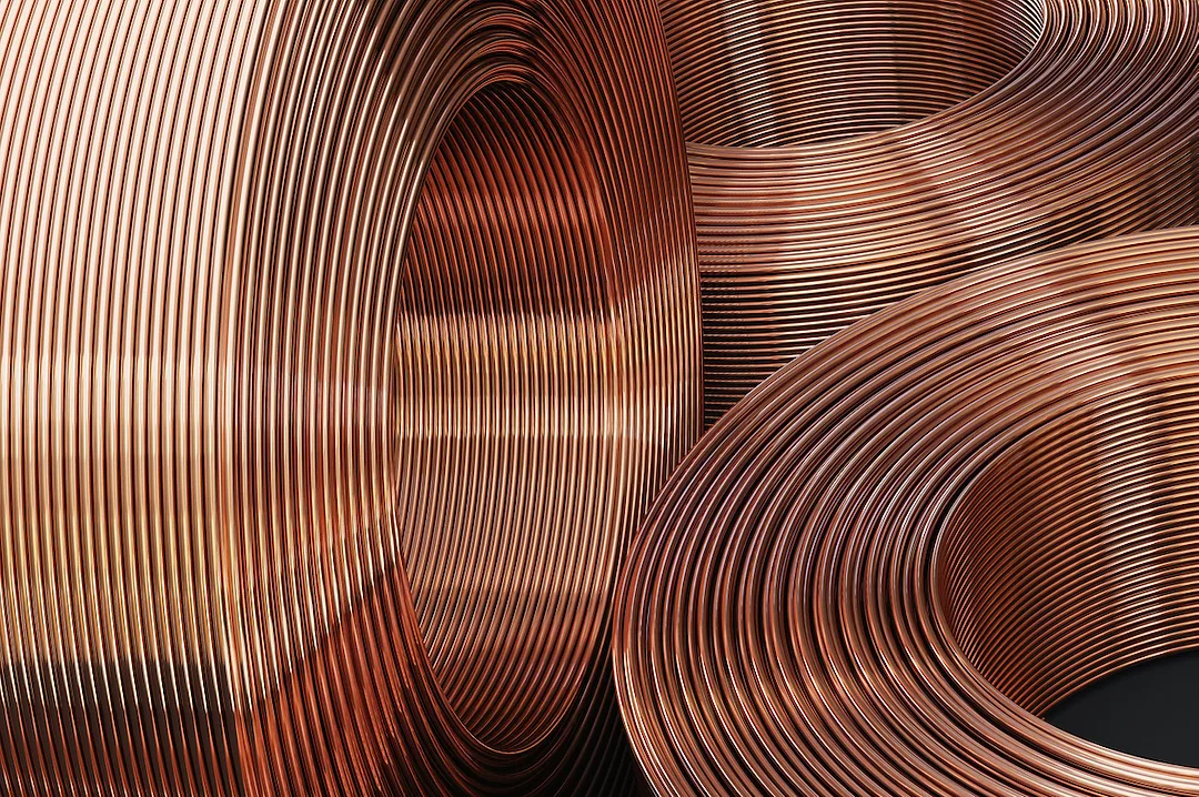 THREE ROUND SPOOLS OF COPPER PIPES CAN BE SEEN. TWO ARE SITTING HORIZONTALLY WHILE ONE IS VERTICAL.
