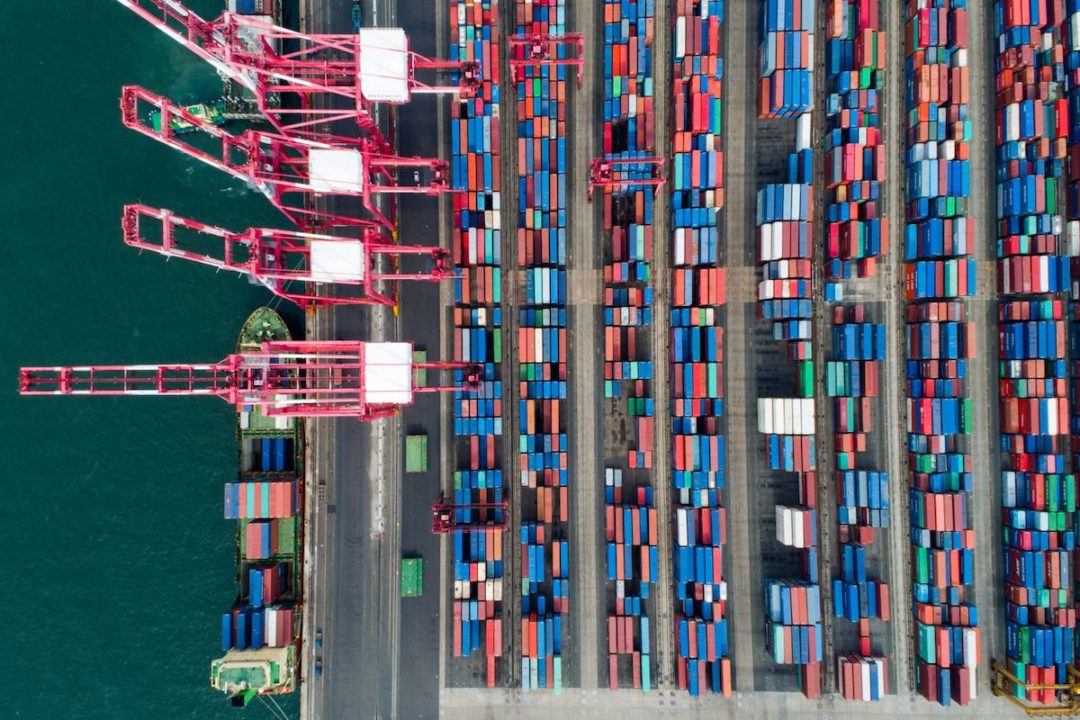 AN AERIAL VIEW OF A PORT FULL OF SHIPPING CONTAINERS AND THREE CRANES IN SOUTH KOREA.