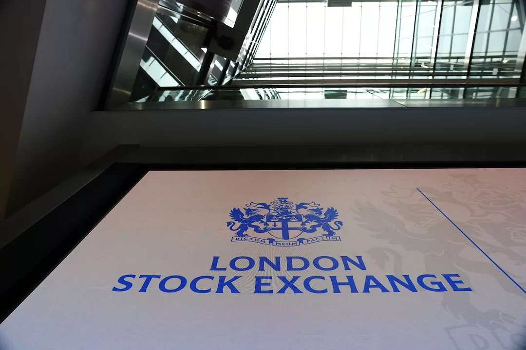 A GROUND VIEW LOOKING UP AT THE LOGO OF THE LONDON STOCK EXCHANGE CAN BE SEEN IN THE ATRIUM OF A LARGE BUILDING.