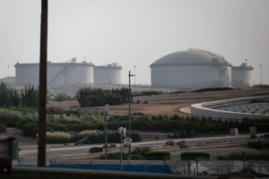THREE LARGE WHITE OIL STORAGE TANKS CAN BE SEEN NEAR A HIGHWAY SURROUNDED BY ROLLING FIELDS.