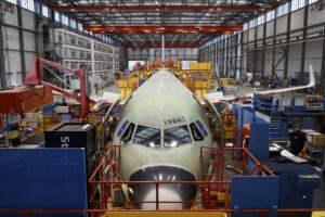 A NEW VERSION OF A PASSENGER AIRCRAFT IS BEING BUILT ON AN ASSEMBLY LINE IN AN AIRBUS FACTORY.