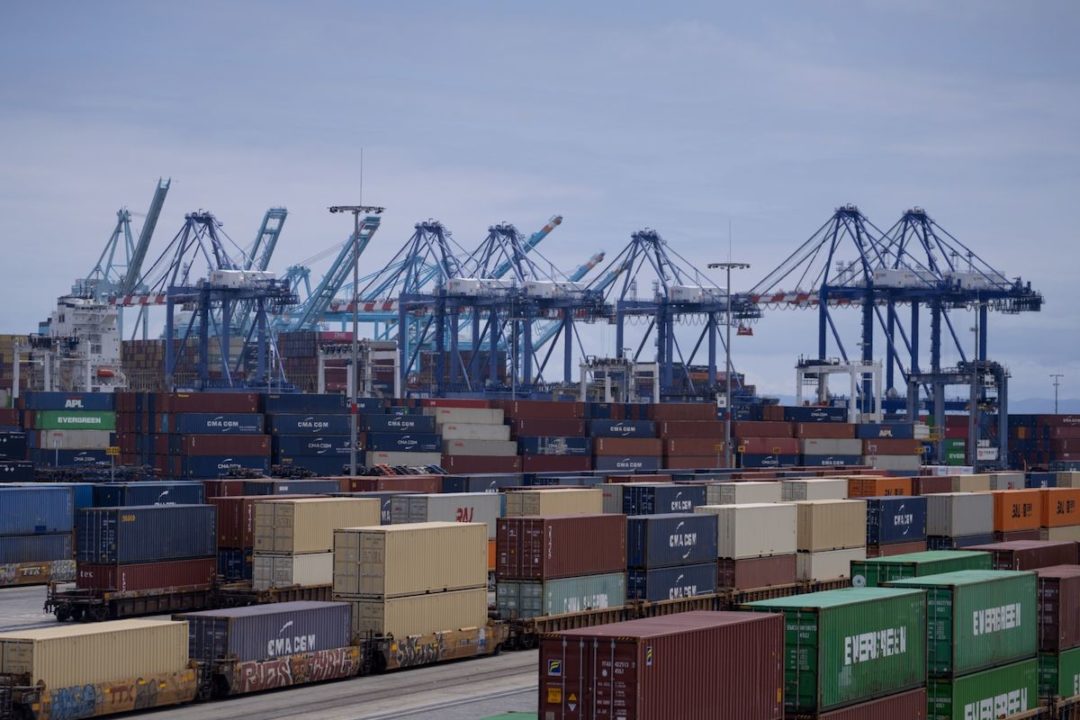 SHIPPING CONTAINERS AND BLUE CRANES CAN BE SEEN AT THE PORT OF LOS ANGELES.