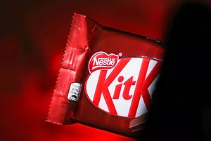THE OUTSIDE OF A KITKAT WRAPPER CAN BE SEEN IN FRONT OF A RED BACKGROUND.
