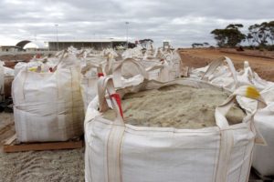 SEVERAL LARGE WHITE BAGS FULL OF LITHIUM CONCENTRATE SIT AT A LITHIUM MINING SITE IN AUSTRALIA.