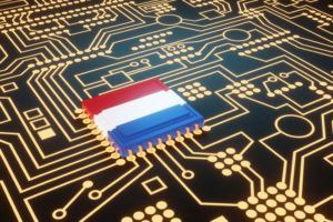 A SEMICONDUCTOR CHIP COLORED AS THE FLAG OF THE NETHERLANDS SITS AT THE CENTER OF A CIRCUIT BOARD
