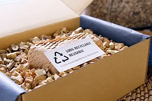 AN OPEN BOX FULL OF PAPER PACKAGING AND A LABEL THAT SAYS 100% REUSABLE RECYCLABLE