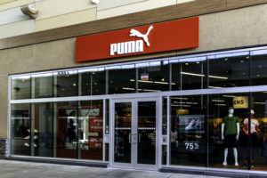THE FRONT OF A PUMA STORE CAN BE SEEN. THE PUMA SIGN ABOVE THE STORE IS RED.